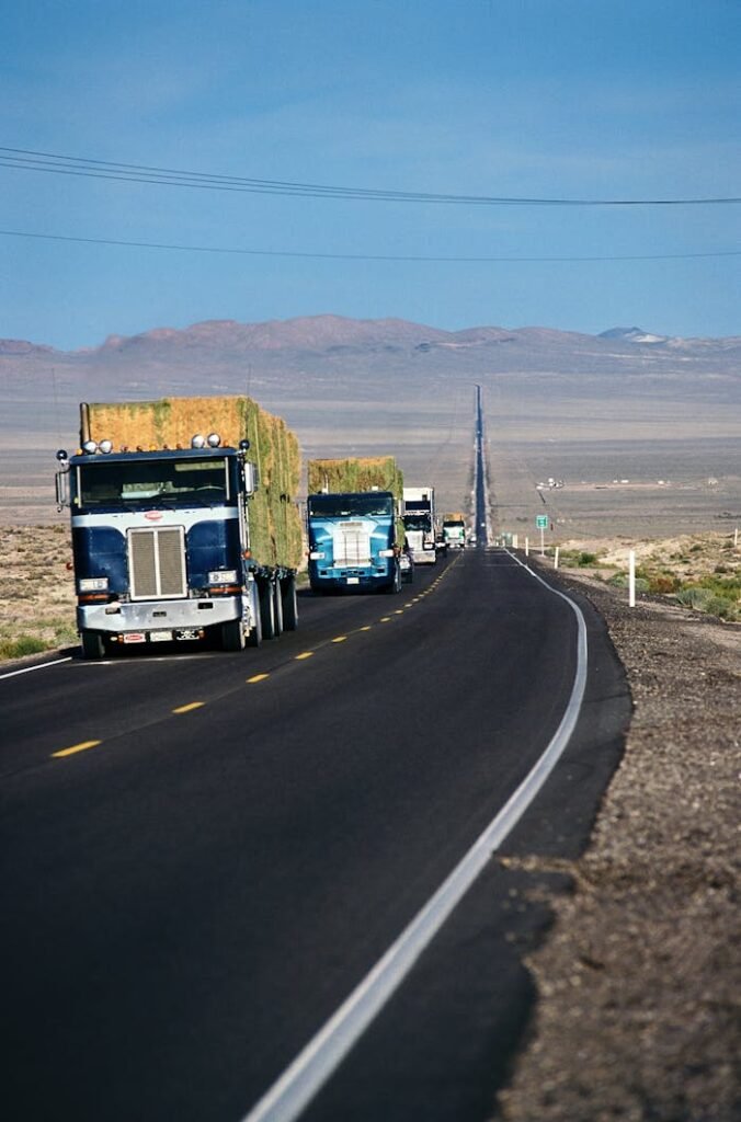 pexels-photo-30344500 Line of semi-trucks driving on a desert highway near Fallon, Nevada, under a clear blue sky.